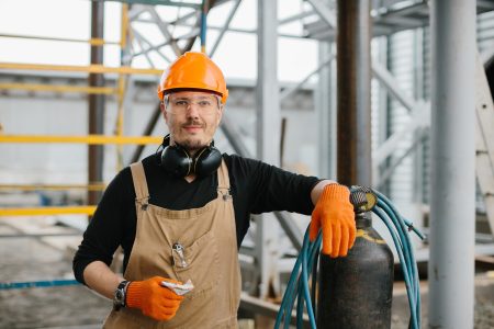 The assembly worker stands near the autogen on the construction site. A look at the camera.
